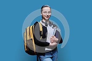 Portrait of teen girl high school student on blue studio background