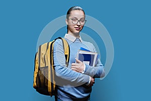 Portrait of teen girl high school student on blue studio background