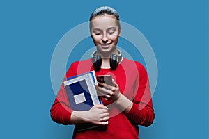 Portrait of teen girl high school student with smartphone on blue background