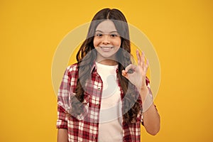 Portrait of teen girl making ok gesture,  background. Young teenager smiling and giving okey sign. Happy cute