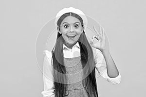 Portrait of teen girl making ok gesture, isolated background. Young teenager smiling and giving okey sign. Happy cute
