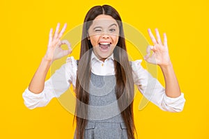 Portrait of teen girl making ok gesture, isolated background. Young teenager smiling and giving okey sign. Happy cute