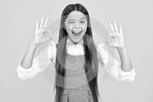 Portrait of teen girl making ok gesture, isolated background. Young teenager smiling and giving okey sign. Happy cute