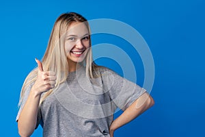 Portrait of teen girl making thumb up gesture on blue background