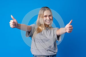 Portrait of teen girl making thumb up gesture on blue background