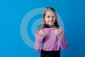 Portrait of teen girl making thumb up gesture on blue background