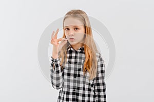 Portrait of teen girl shushing, showing shhh, taboo sign, press finger to lips with concerned face, keep quiet, stands over white