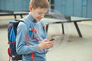 Portrait of teen school boy browsing in internet using cell phone