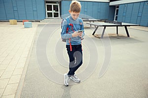 Portrait of teen school boy browsing in internet using cell phone