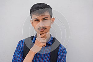 Portrait of teen thinking man looks up with hand near face.teen student.