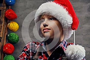 Portrait of teenage boy dressed in Santa`s hat and a plaid shirt.