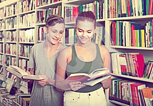 Portrait of teenage boy and girl customers looking at open book