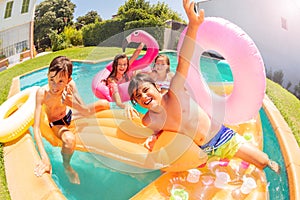 Cute boy having fun with friends in swimming pool