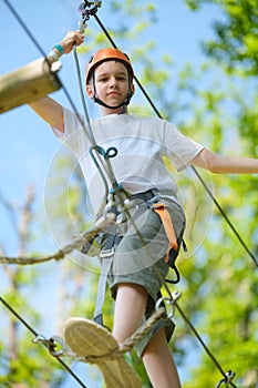 Portrait of teenage boy having fun at outdoor extreme adventure park. Active childhood, playing outdoors.