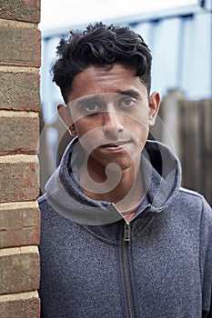 Portrait Of Teenage Boy Leaning Against Wall In Urban Setting