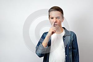 Portrait of teenage boy picking nose, standing over white background