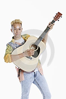 Portrait of a teenage boy playing guitar over gray background