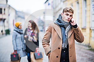 A portrait of teenage boy with smartphone on the street in winter.