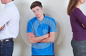 Portrait Of Teenage Boy Standing Between Parents Who Are Ignoring Each Other