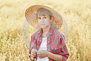 Portrait of teenage farm boy wearing red checkered shirt and yellow wide-brimmed natural straw hat