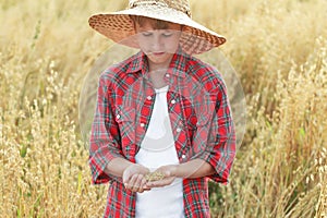 Portrait of teenage farmer boy is checking oat or Avena sativa seeds in cupped palms