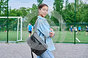 Portrait of teenage female student looking at camera, school stadium background