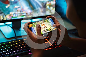 Portrait of teenage gamer boy playing video games on smartphone