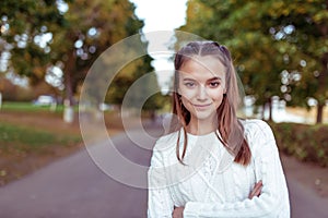 Portrait of a teenage girl of 12 years old, in summer in park, casual clothes, white knitted sweater, free space for