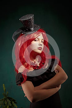 Portrait of a teenage girl in a black dress with a red wig and in a carnival hat. Christmas new year