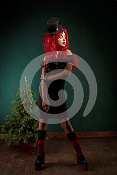 Portrait of a teenage girl in a black dress with a red wig and in a carnival hat. Christmas new year