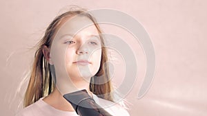 portrait teenage girl with blond hair on a light background dries her hair, close up on the face