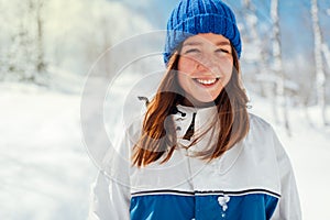Portrait of a teenage girl in blue winter sports suit on a background of snowy trees