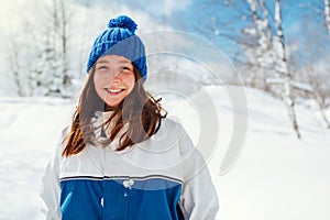 Portrait of a teenage girl in blue winter sports suit on a background of snowy trees