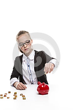 Portrait of Teenage Girl in Dark Jacket Putting Coin Into The Piggybank For Savings