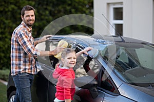 Teenage girl and father washing a car on a sunny day