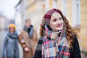 A portrait of teenage girl with headband and scarf on the street in winter.