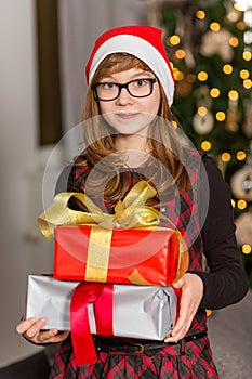 Portrait of teenage girl holding stack of Christmas presents