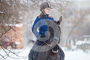 Portrait of teenage girl riding raven horse in winter