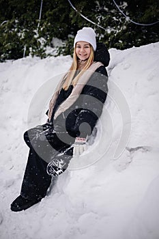 Portrait of a teenage girl sitting in a snowdrift in winter.