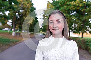 Portrait of teenage girl, summer in park, casual wear, white knitted sweater, free space for copy text. Weekend break