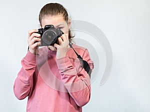Portrait of teenage girl taking picture with DSLR camera, front view during shooting, grey background, copyspace