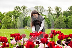 Portrait teenage girl walking in spring park with colorful flowers outdoors