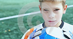 Portrait of teenage goal keeper holding ball on school soccer pitch