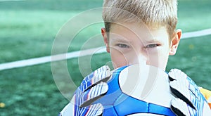 Portrait of teenage goal keeper holding ball on school soccer pitch