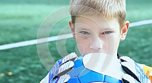 Portrait of teenage goal keeper holding ball on school soccer pitch