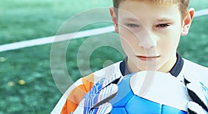 Portrait of teenage goal keeper holding ball on school soccer pitch