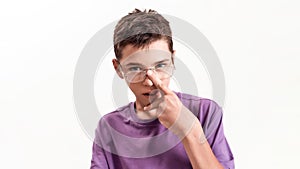 Portrait of teenaged disabled boy with cerebral palsy looking at camera, adjusting his glasses isolated over white