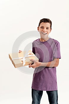 Portrait of teenaged disabled boy with cerebral palsy smiling while holding a gift box, present standing isolated over