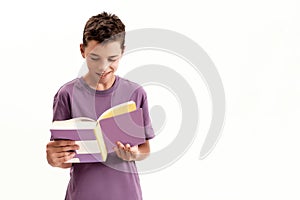 Portrait of teenaged disabled boy with cerebral palsy smiling while holding and reading a book, standing isolated over