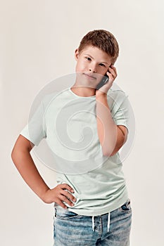 Portrait of teenaged disabled boy with Down syndrome looking at camera while talking on the phone, standing 